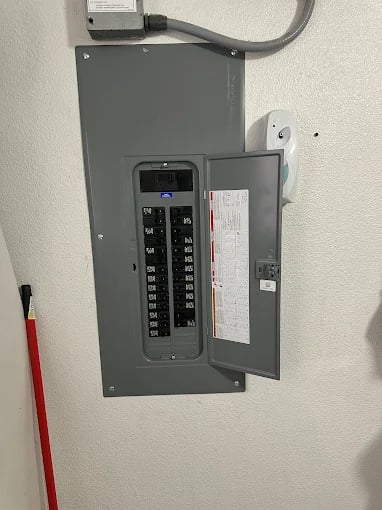 Gray electrical panel with circuit breakers mounted on wall